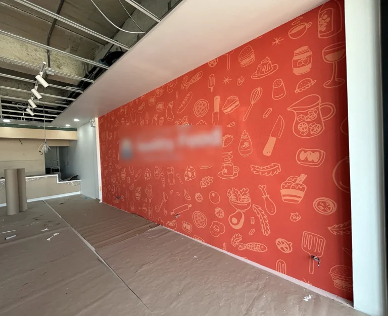 Printed orange wallcovering with food illustrations installed as a retail store feature wall
